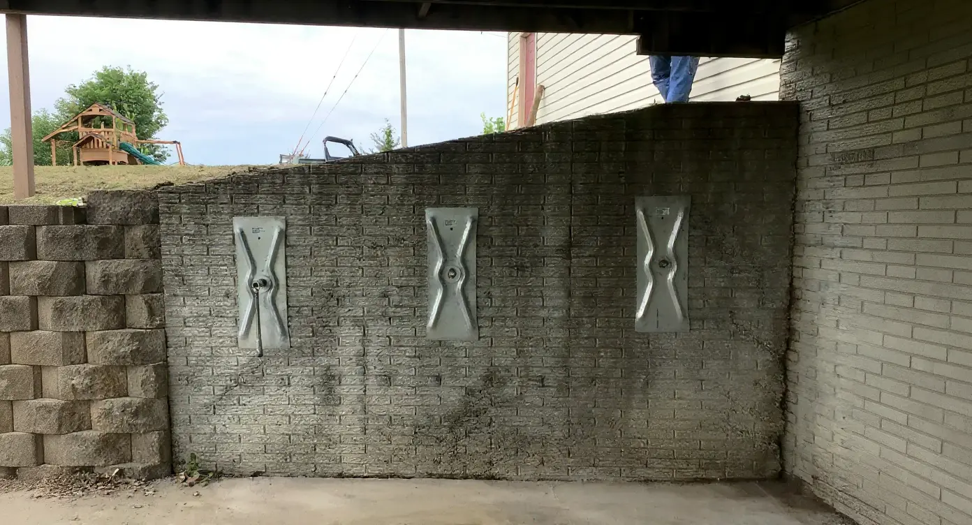 Stage 1-2 bowing basement wall with hairline horizontal crack along mortar joint and tape measure showing less than half-inch inward deflection — the early intervention window for wall stabilization