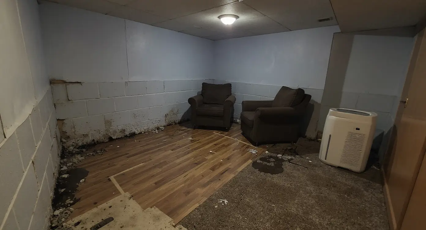 Finished basement with flood damage — warped flooring, water-stained drywall, and ruined baseboards