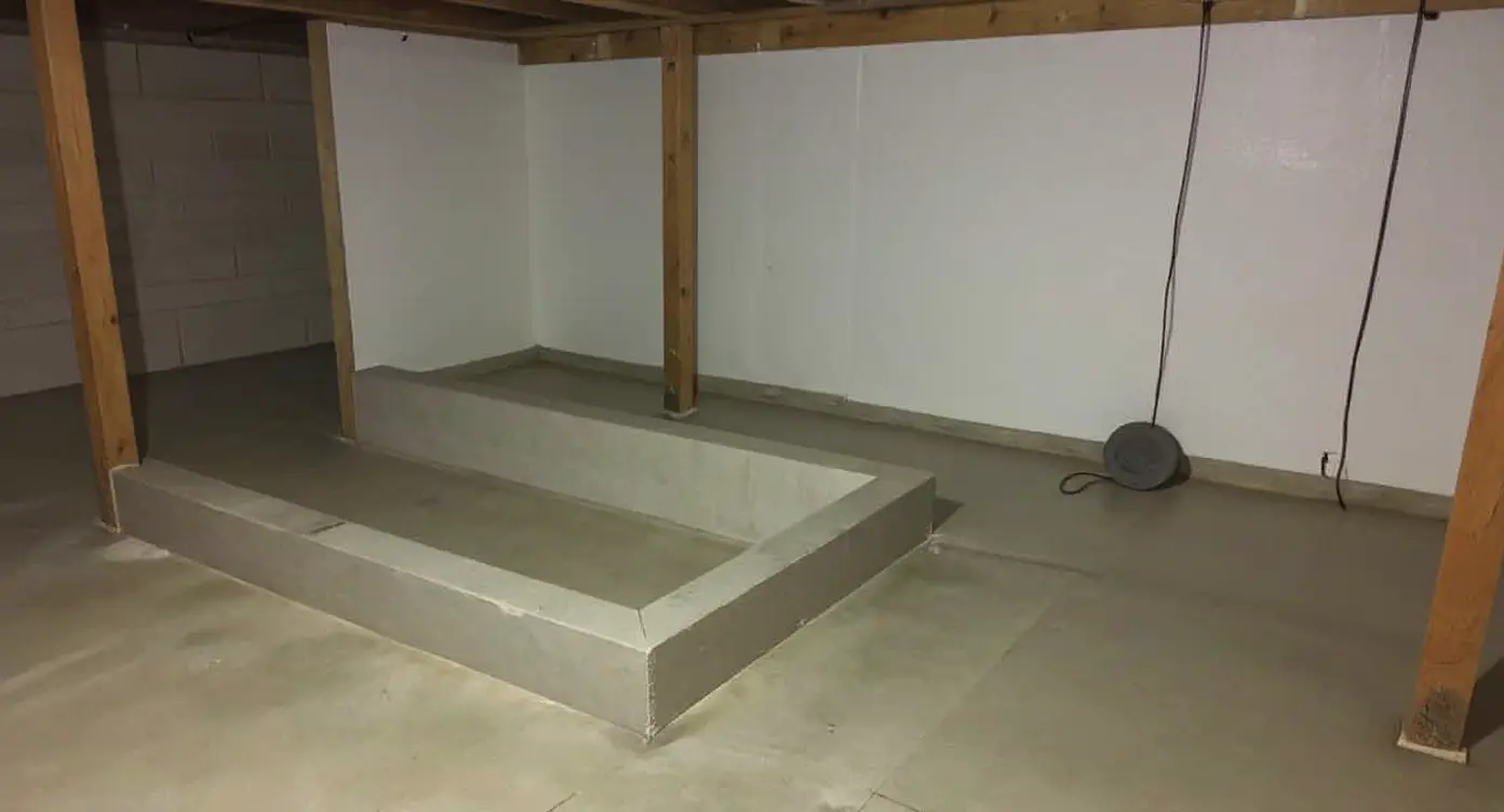 Completed interior basement waterproofing system with sealed perimeter drain channel, vapor barrier on walls, and sump pit — a professional installation that intercepts water before it reaches the living space
